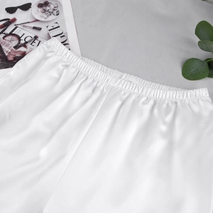 Détail d'un pantalon en satin blanc avec taille élastique et finition perle brillante