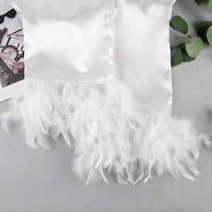Détail de la manche en satin de soie avec plumes d'autruche sur vêtement blanc