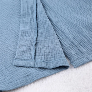 Detailed close-up of dark blue crinkled cotton crepe fabric texture and neat hem stitching