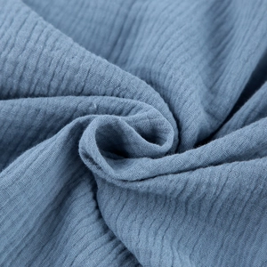 Close-up of blue muslin crepe cotton fabric texture with natural soft wrinkles