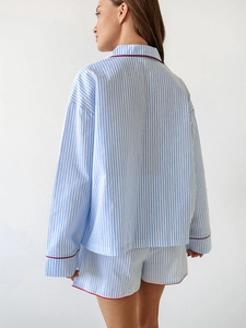Detail of blue and white striped cotton pajamas with contrast red piping on the cuffs