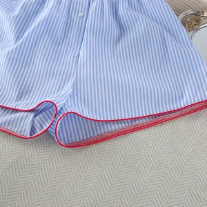 Macro shot of striped cotton pajama shorts with red piping and single button detail