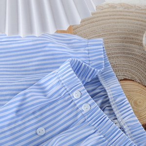 Close-up of blue striped cotton pajama pants with elastic waistband and button detail