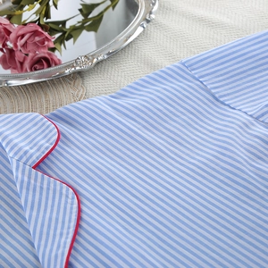 Detail of blue and white striped cotton pajamas with contrast red piping on the collar