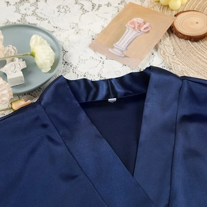 Detailed view of dark blue satin fabric texture and V-neckline of a luxurious bathrobe