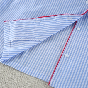 Detailed view of blue striped cotton pajama set with red piping and white buttons