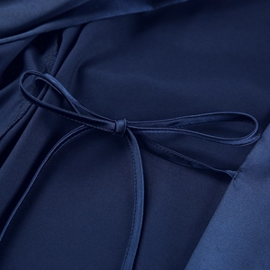 Detailed close-up of a navy blue satin robe featuring a delicate matching silk bow tie