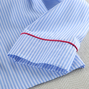 Detail of blue and white striped cotton pajama cuff featuring contrast red piping trim