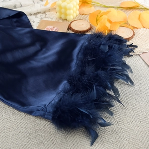 Close-up of luxurious blue satin robe featuring thick feather trim on a textured background