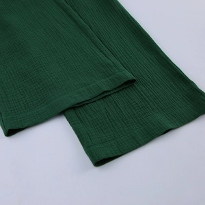 Dettaglio del tessuto in cotone crepe verde bosco con trama naturale e cuciture di precisione