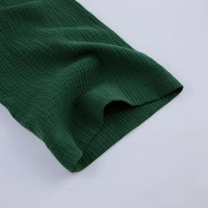 Dettaglio del tessuto in cotone stropicciato verde scuro con trama morbida e traspirante