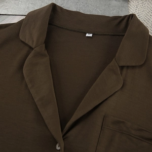 Detail view of the V-neckline, chest pocket, and fabric texture of dark brown modal sleepwear
