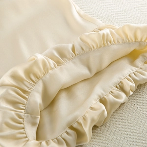 Close-up of champagne satin fabric showing elegant ruffle details and silky texture