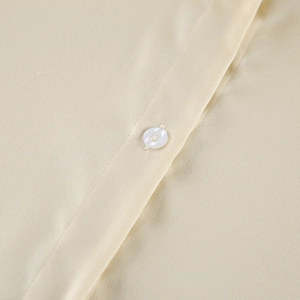 Detailed view of high-quality satin fabric and a polished button on the beige pajama top