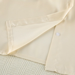 Detail of silk satin beige pajama set showing fine stitching and transparent button