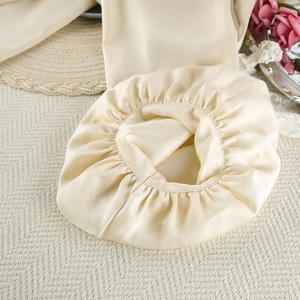 Detail shot of a champagne satin sleeping cap with smooth silk texture and elastic band