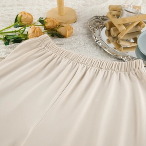 Detail of the elastic waistband on cream lounge pants featuring soft draped fabric