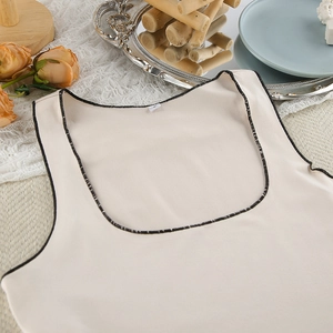 Detail of apricot sleepwear top with black contrast piping and soft ribbed texture