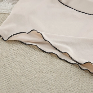 Detail of apricot lounge top hem with delicate black contrast lettuce edge stitching