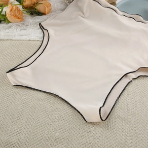Detail of apricot tank top featuring black wavy scalloped edges and fine knit texture