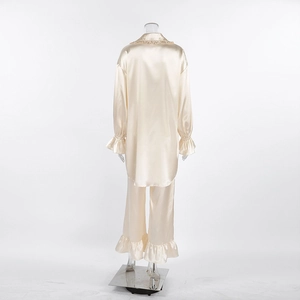 Achteraanzicht van crèmekleurige satijnen pyjama met elegante ruches aan mouw en zoom