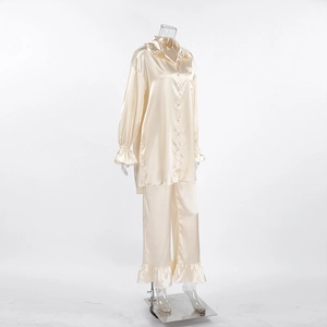 Detailweergave van champagne satijnen pyjama met ruches aan de mouwen en glanzende stof
