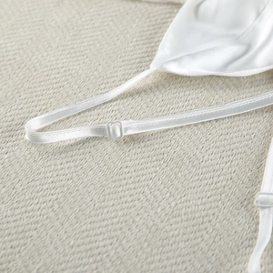 Detail of adjustable straps on a white silk satin camisole with metal buckles