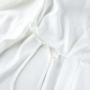 Detail of elegant white satin pajama robe featuring a delicate bow-tie waist closure
