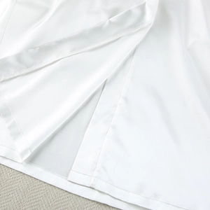 Detail view of the side slit on white satin sleepwear robe showing fabric texture