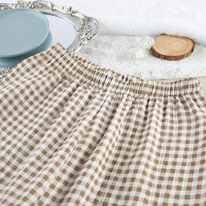 Detail view of the elastic waistband on coffee and white plaid cotton pajamas with lace