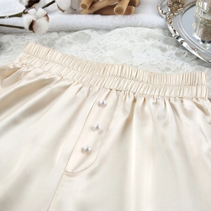 Detail van champagne satijnen lounge shorts met parelknopen en elastische tailleband