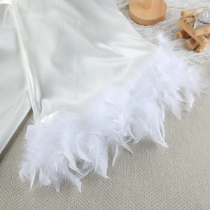 Detailed view of white satin fabric with luxurious feather trim on lounge set hem