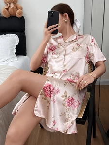 Close-up of pink satin pajama shirt with delicate floral prints and buttoned lapel