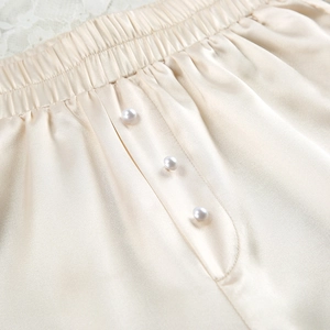 Detail van de champagne satijnen lounge shorts met elastische taille en parelknopen