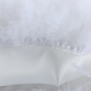 Detailed macro view of soft white faux feathers and silky satin fabric texture