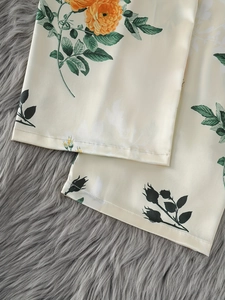 Gros plan détaillé de l'imprimé floral orange sur le pantalon de pyjama en satin soyeux
