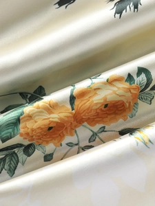 Gros plan sur un tissu en satin champagne avec imprimé rose jaune et texture soyeuse