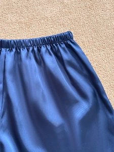 Detailed close-up of dark blue satin pajama shorts with elastic waistband and silky texture