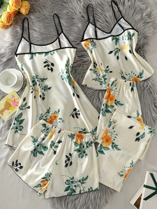 Pyjama 4 pièces en satin crème à imprimé floral rose posé à plat sur un tapis en fourrure