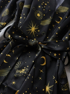 Detail of black silk pajama robe with gold moon and star patterns and satin waist tie