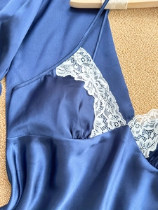 Detail of navy blue satin pajama top featuring white lace trim and silky texture