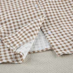 Detailed macro view of the brown gingham cotton fabric and button sewing on pajama top