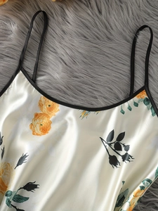 Détail d'un caraco en satin imprimé floral avec bordure noire sur fond en peluche