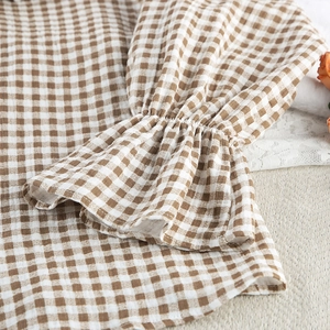 Detail of ruffled elastic cuffs on brown checkered cotton pajama with woven texture