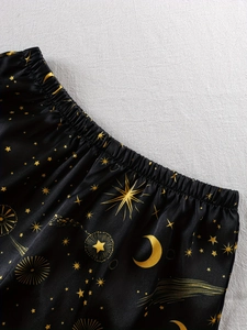 Detailed close-up of celestial gold star and moon prints on black satin pajama shorts