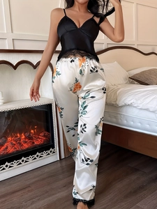 Detailed close-up of lace trim on black camisole and floral satin trousers pajama set