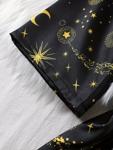 Detail of silk pajamas featuring gold moon and star patterns with neat hem stitching