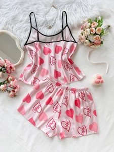 Detail of pink satin camisole set with heart and love prints on white rumpled bedding