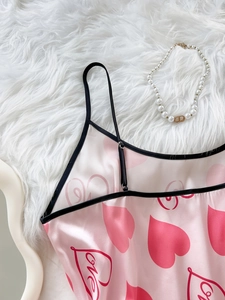 Detail of pink satin sleepwear with heart prints and adjustable black shoulder straps