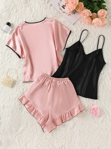 Detailed flat lay of pink and black contrast 3-piece silk pajama set with ruffle shorts